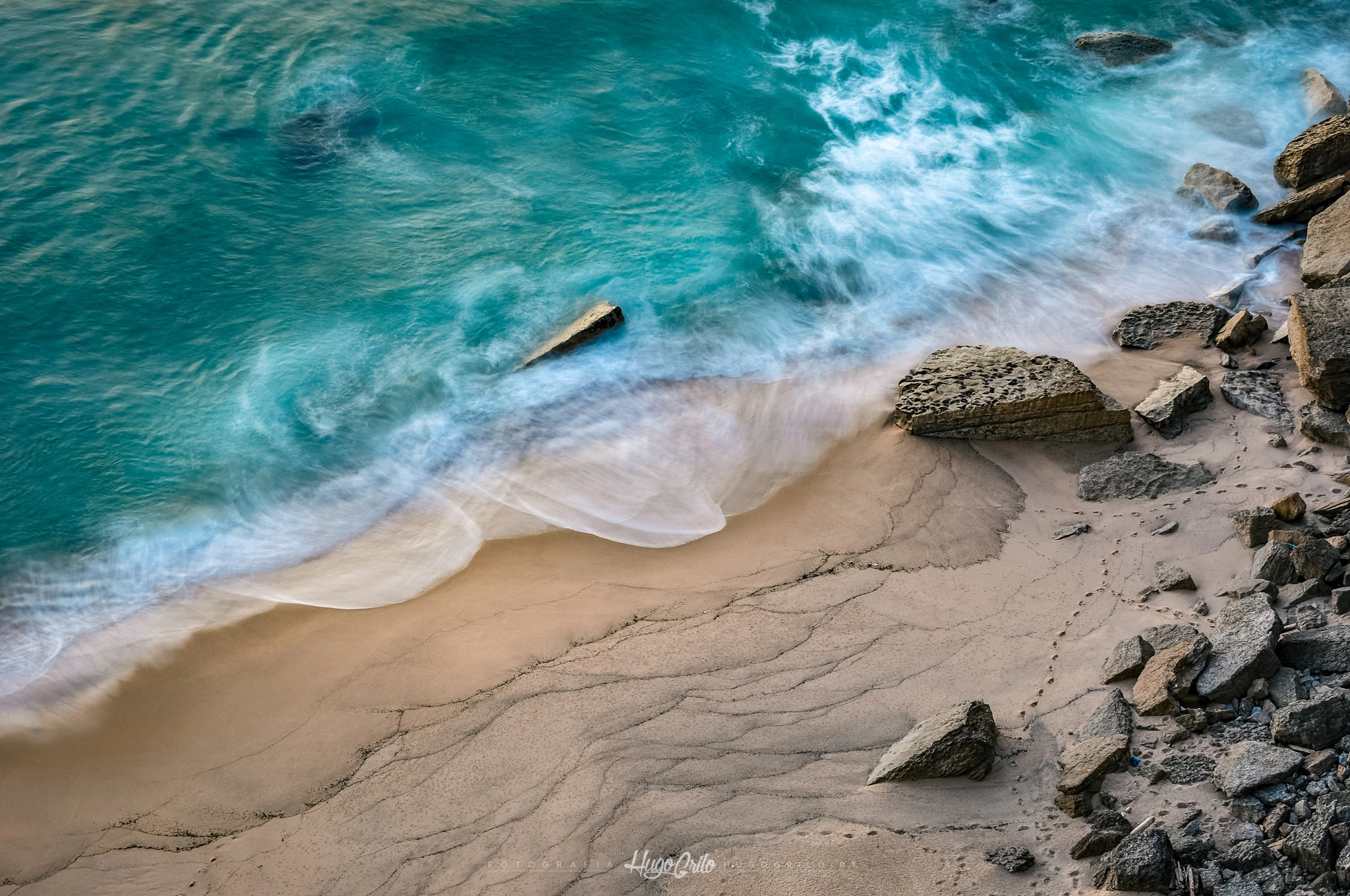 Ondas junto a uma praia de areia e rochas